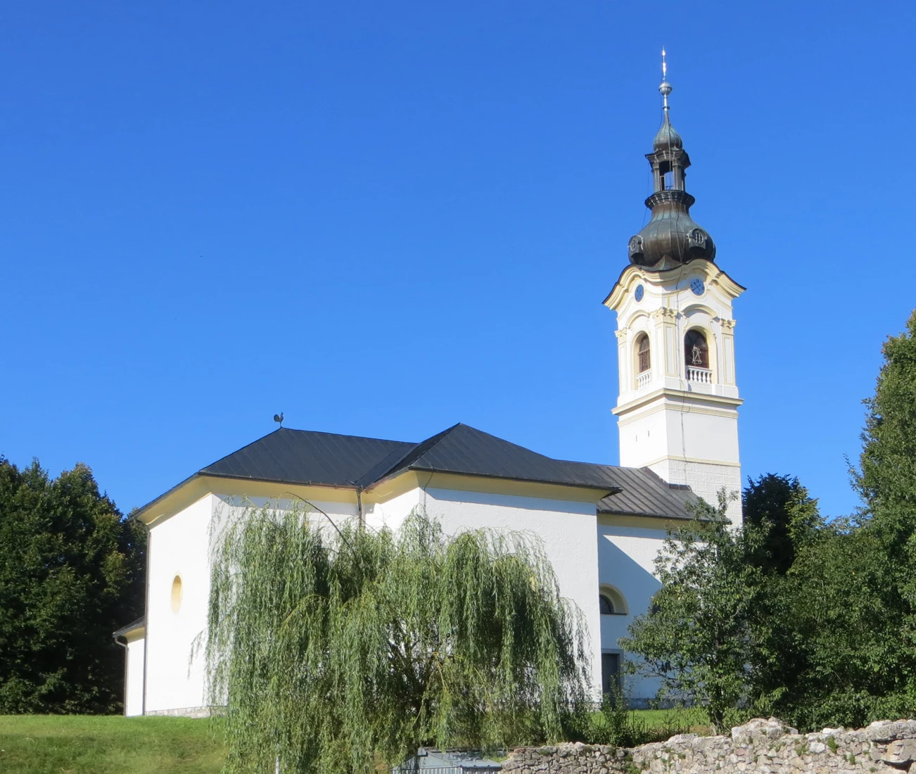 Cerkev Marijinega vnebovzetja v Velikih Blokah z baročnim zvonikom in odprto lanterno.