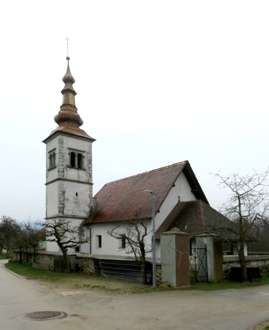 Cerkev sv. Florijana v Studenčicah z visokim čebulastim zvonikom, vhodno lopo in nizkim obzidjem.