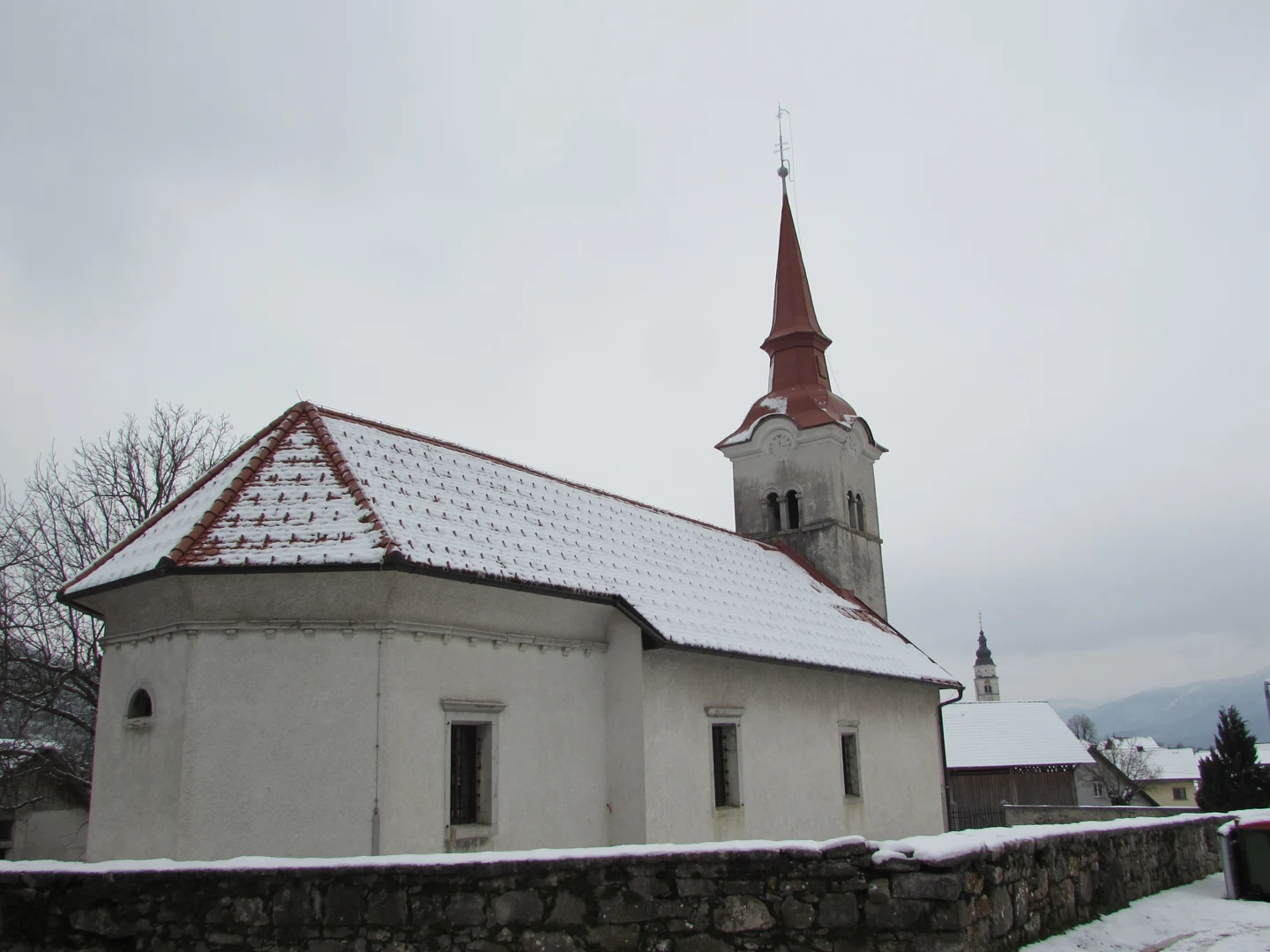 Cerkev sv. Roka v Cerknici s prezbiterijem, ladjo in zvonikom za kamnitim obzidjem