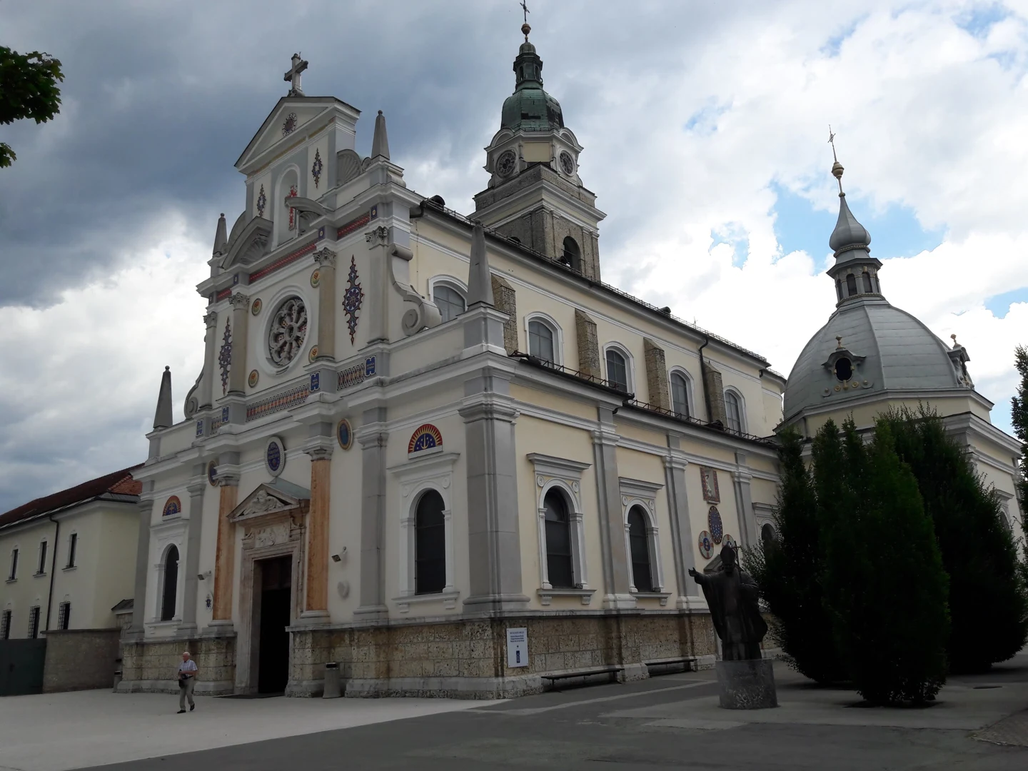 Pročelje in bočna stavba bazilike na Brezjah z zvonikom in kupolo.