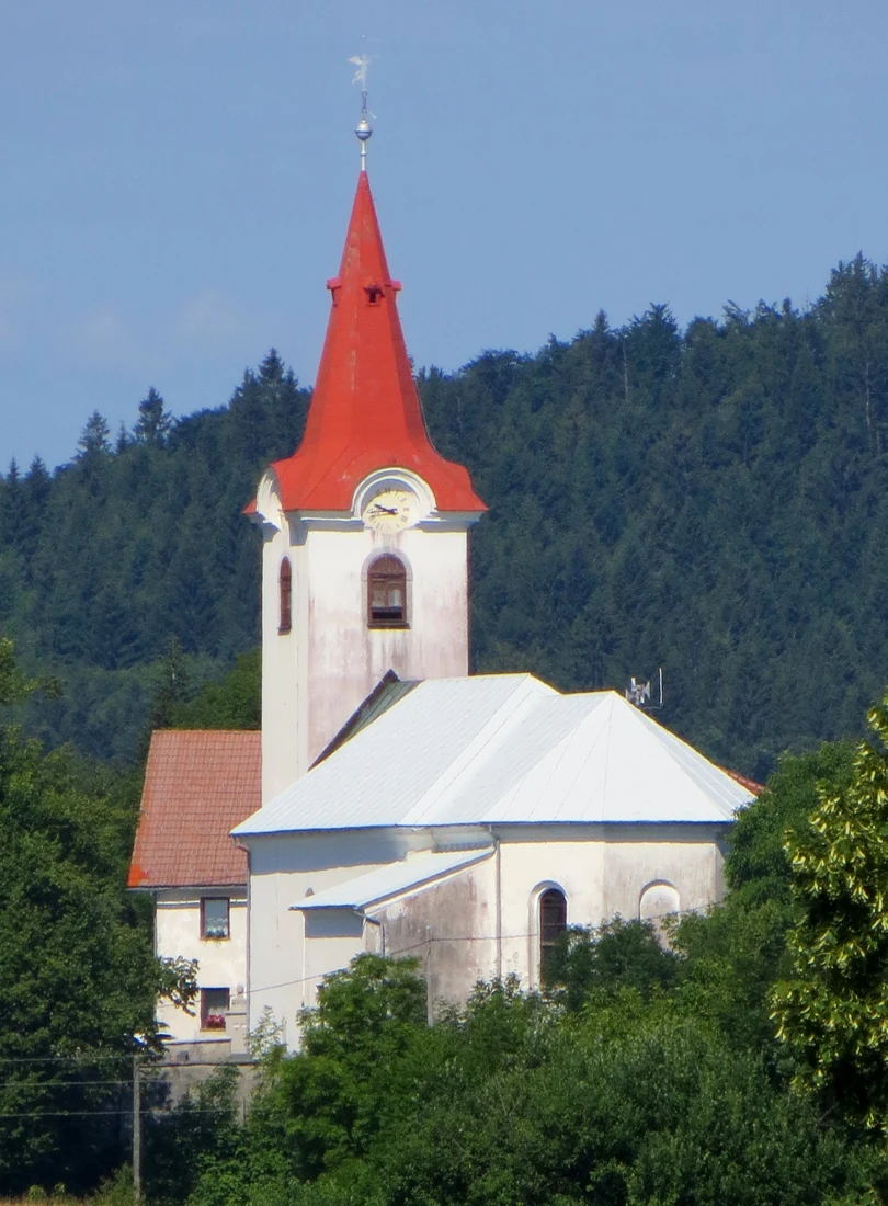 Cerkev sv. Vida nad Cerknico s svetlim prezbiterijem in zvonikom z rdečo koničasto streho