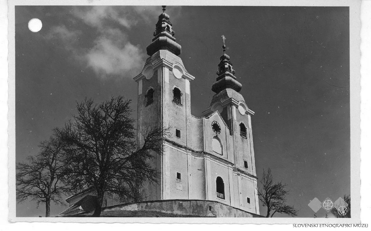 Zgodovinska črno-bela razglednica dvostolpnega pročelja cerkve sv. Križa na Gori Oljki z ohranjenimi muzejsko-arhivskimi oznakami.