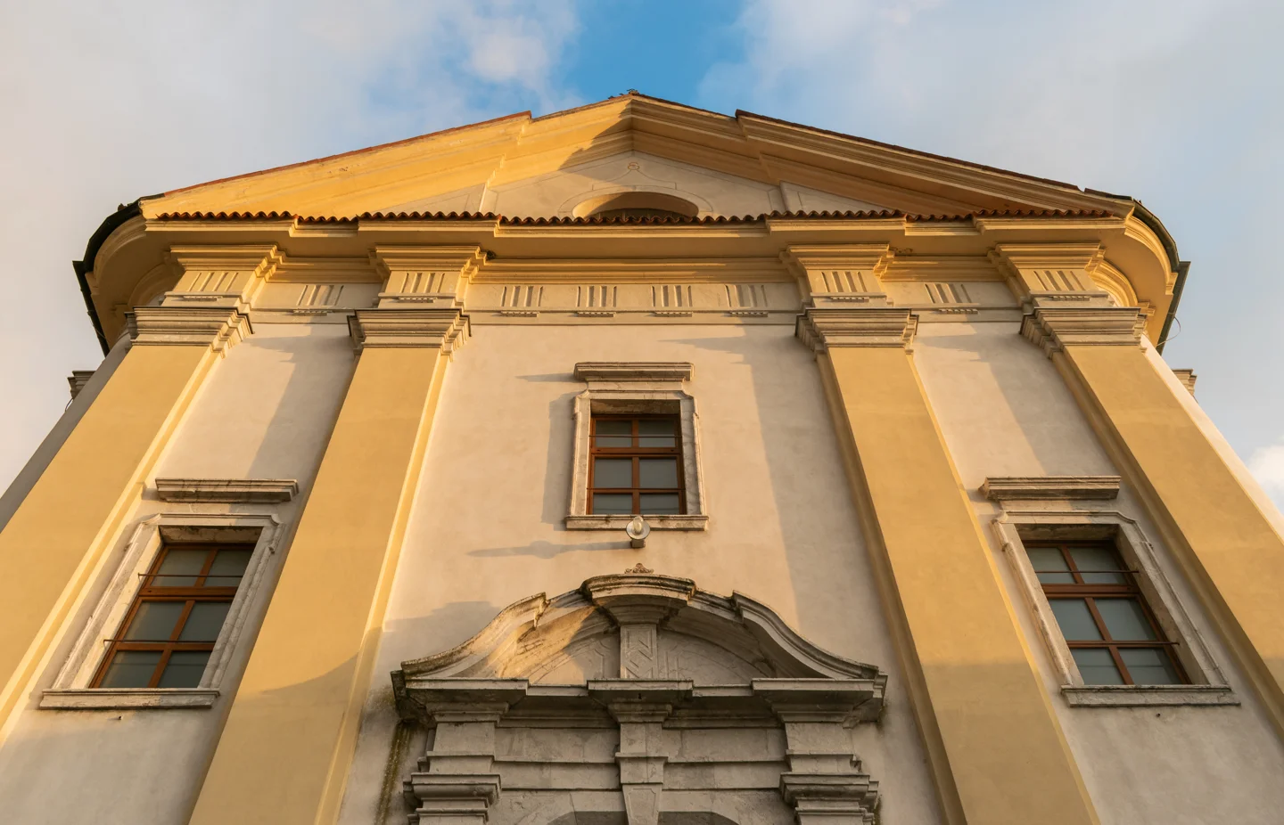 Zgornji del pročelja cerkve sv. Silvestra s pilastri, tremi okni in trikotnim zaključkom.